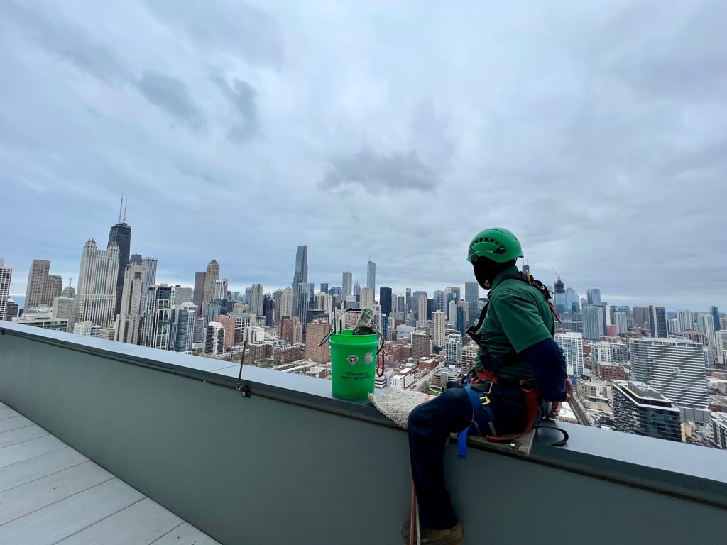 A window washer checks their safety equipment on top of a Chicago high rise building