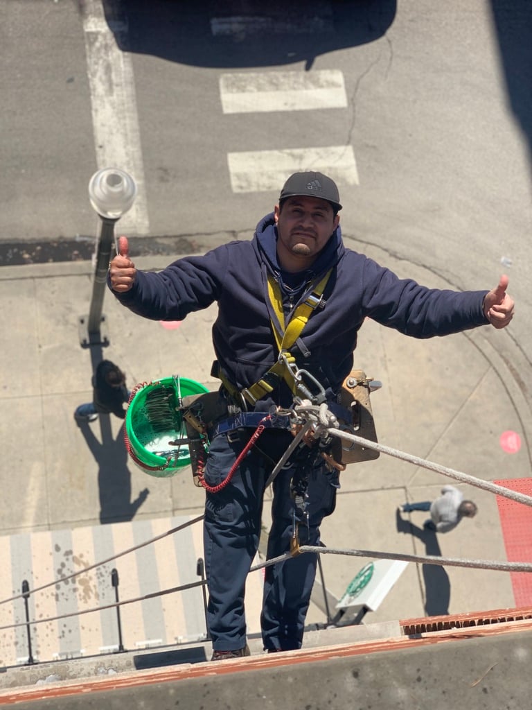 Window washer using proper safety equipment while descending down side of building