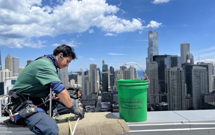 A window washer checks their safety gear ontop of a Chicago skyscraper.
