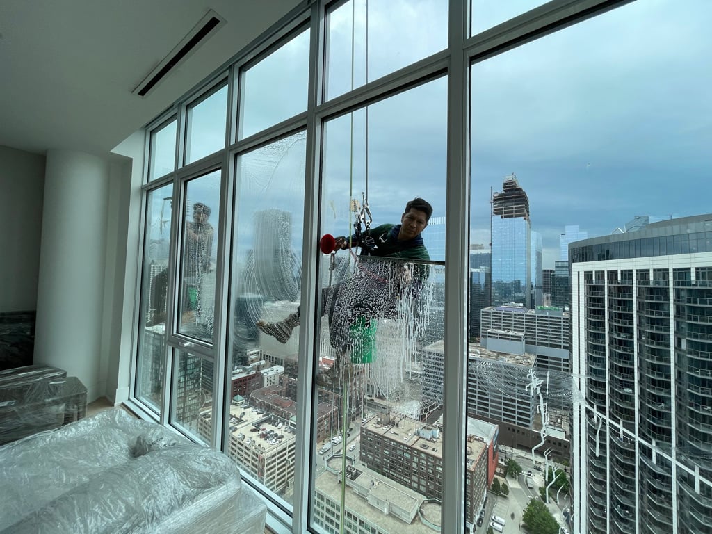 Using a squeegee to clean high rise apartment windows in Chicago