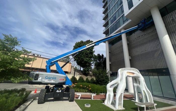 Ascent using Genie articulated boom lift to clean a luxury apartment building