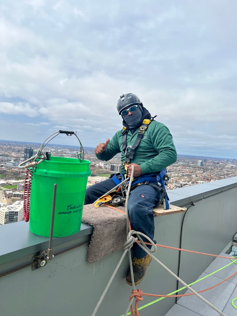 Window washer strapped into a safety harness on top of a building