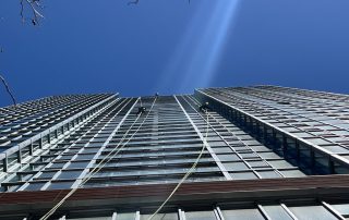 Using OSHA safety equipment window washers clean a high rise apartment building