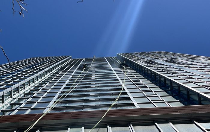 Using OSHA safety equipment window washers clean a high rise apartment building