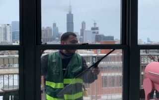 Window washer cleaning apartment building windows with squegee