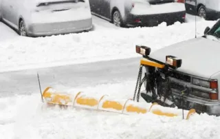 Commercial snow removal truck with front-mounted plow clearing a parking lot in Chicago during winter.
