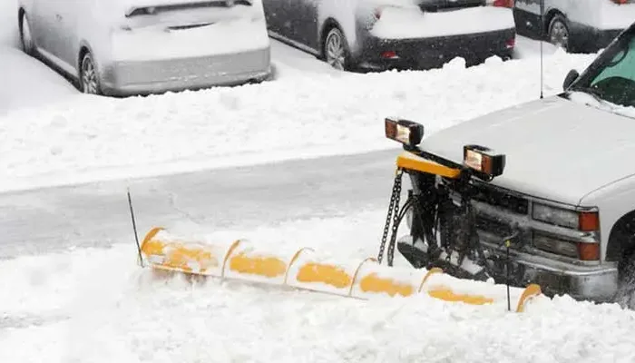 Commercial snow removal truck with front-mounted plow clearing a parking lot in Chicago during winter.