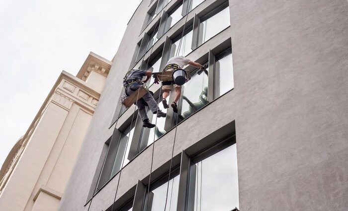 Technician performing high-rise window cleaning using rope access on a building exterior in Chicago.
