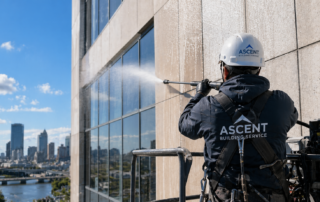 Professional exterior building cleaning in Milwaukee WI with technician performing high-rise pressure washing on commercial facade